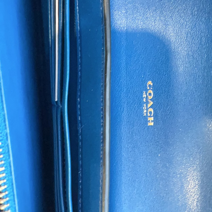 Blue Coach wallet with gold logo on a blue background
