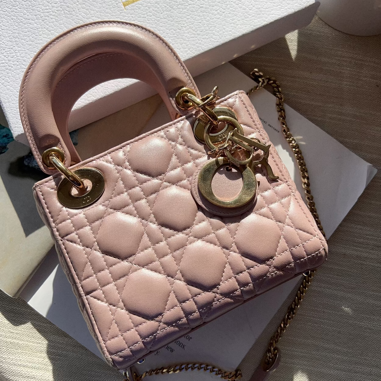 Pink handbag with gold chain and hardware on a light background