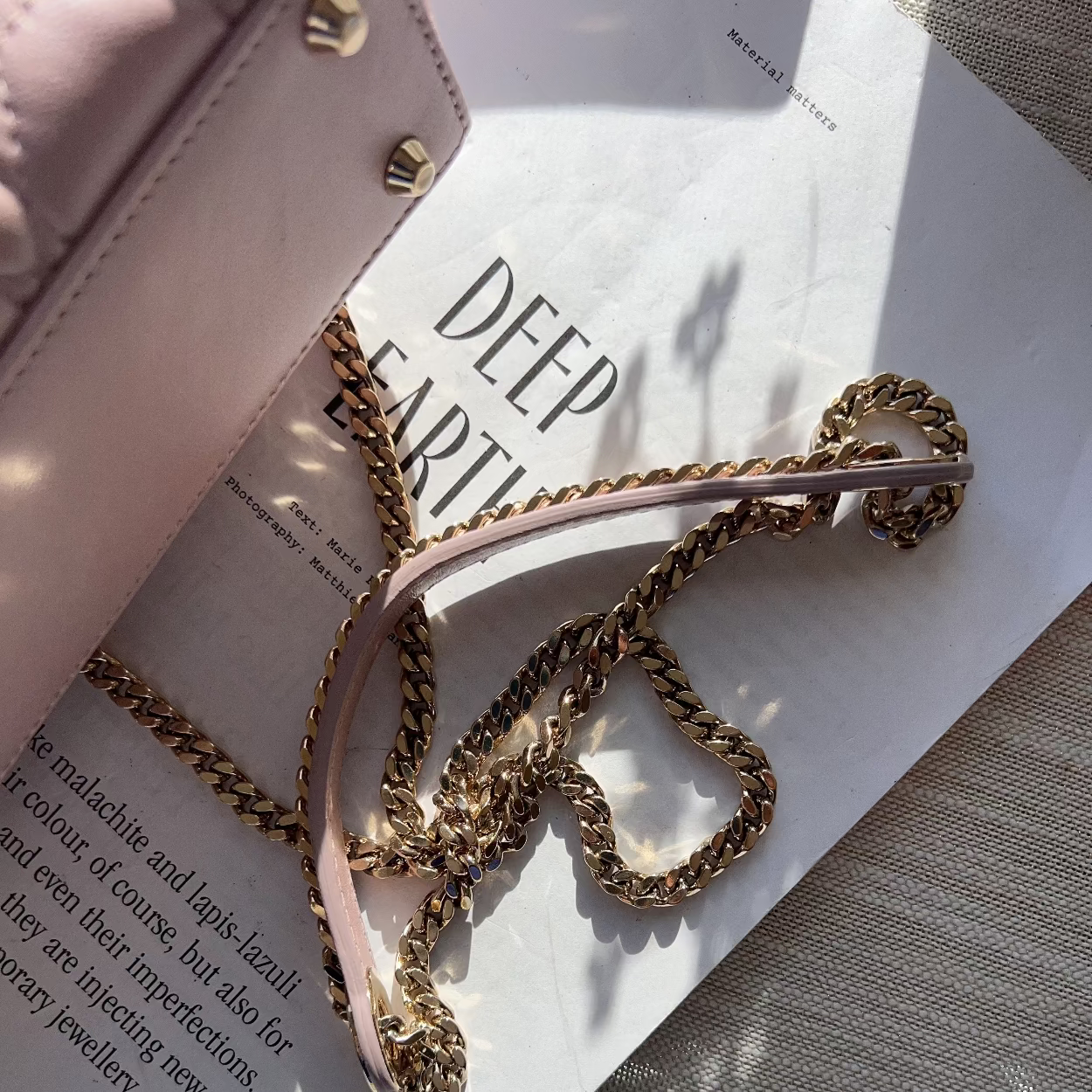Gold chain headband on a magazine with a pink handbag
