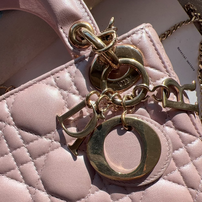 Close-up of a quilted handbag with gold chain and 'D' logo charm.