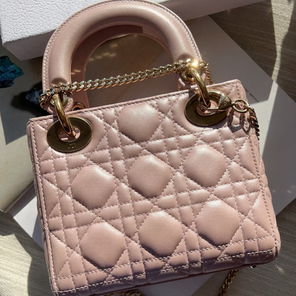 Pink handbag with gold chain and hardware on a light surface