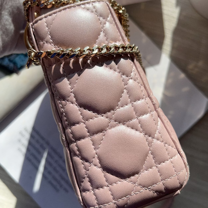 Pink quilted phone case with gold chain held by a hand