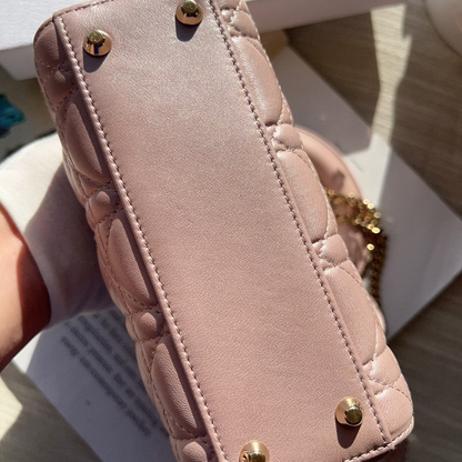 Pink quilted phone case with gold accents held by a hand on a light background
