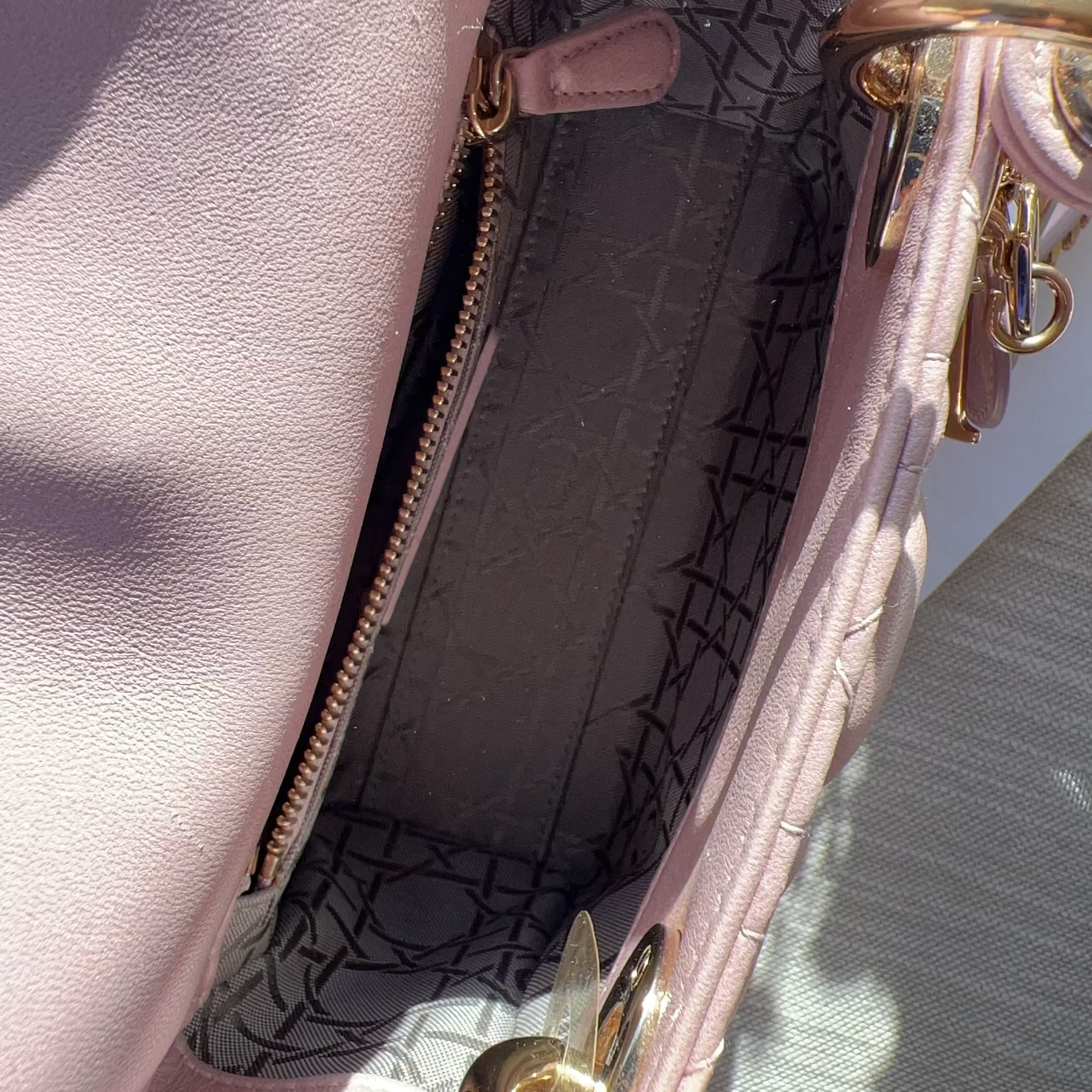 Close-up of a pink handbag with gold hardware and a patterned interior.