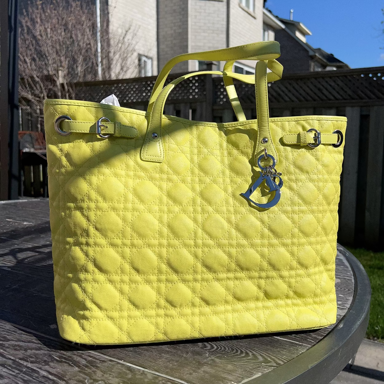 Yellow quilted handbag on a table outdoors with a house in the background
