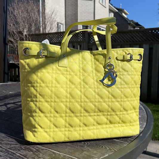 Yellow quilted handbag on a table outdoors with a house in the background