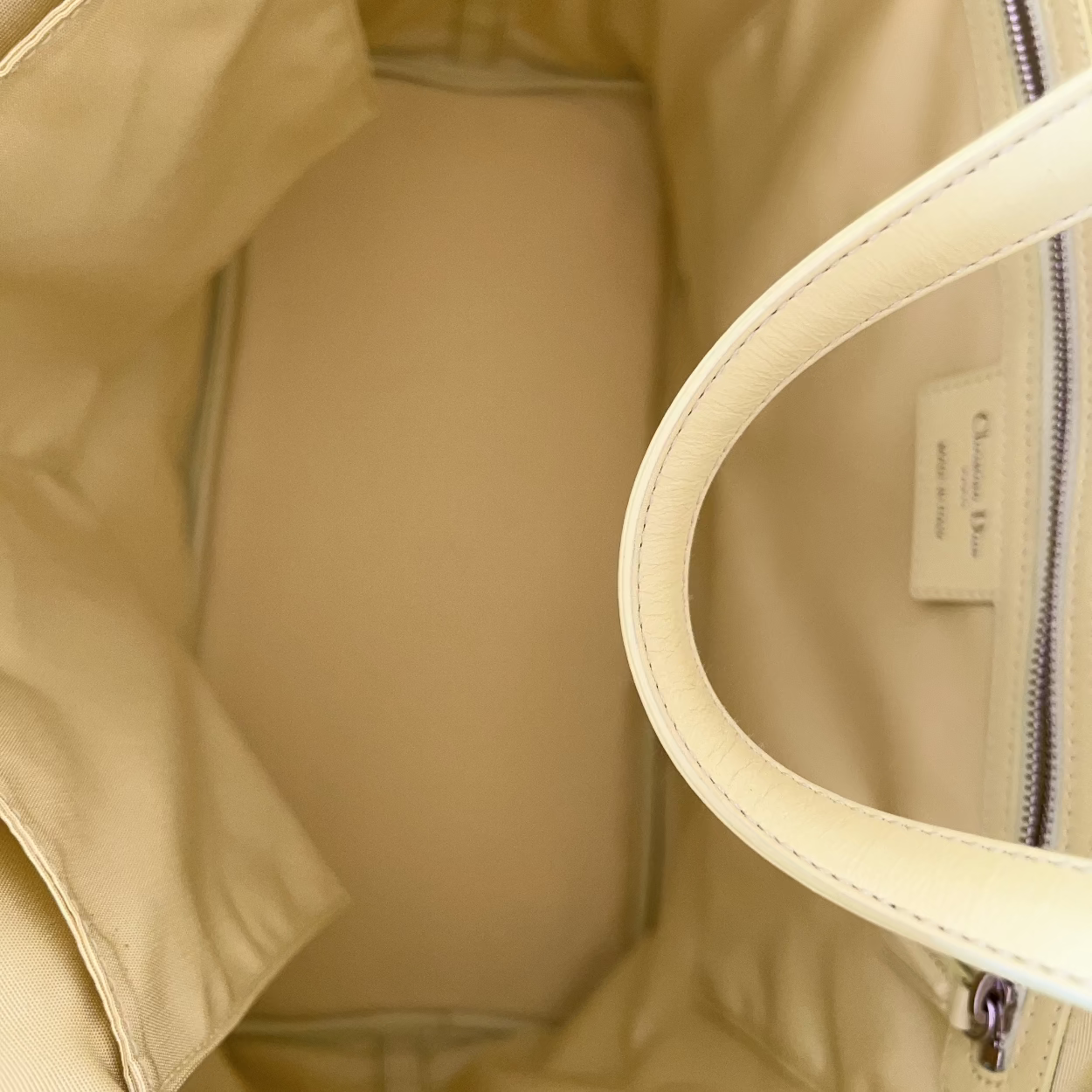 Close-up of a beige jacket with a zipper and handle
