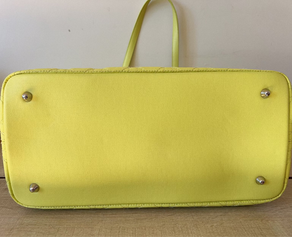 Yellow handbag with silver studs on a wooden surface
