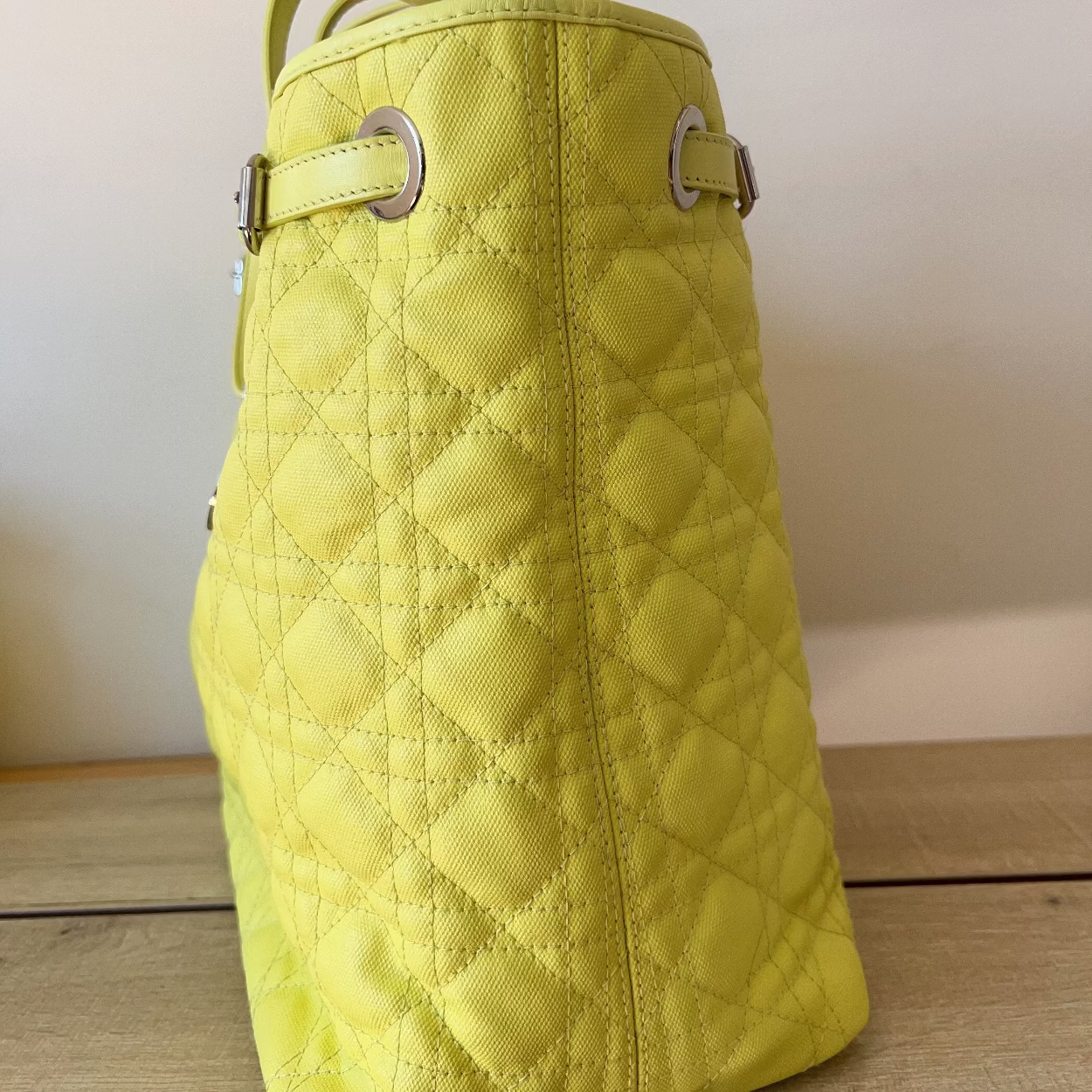 Yellow quilted handbag on a wooden surface with a neutral background