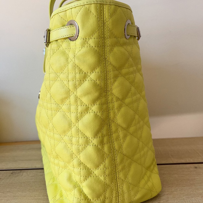 Yellow quilted handbag on a wooden surface with a neutral background