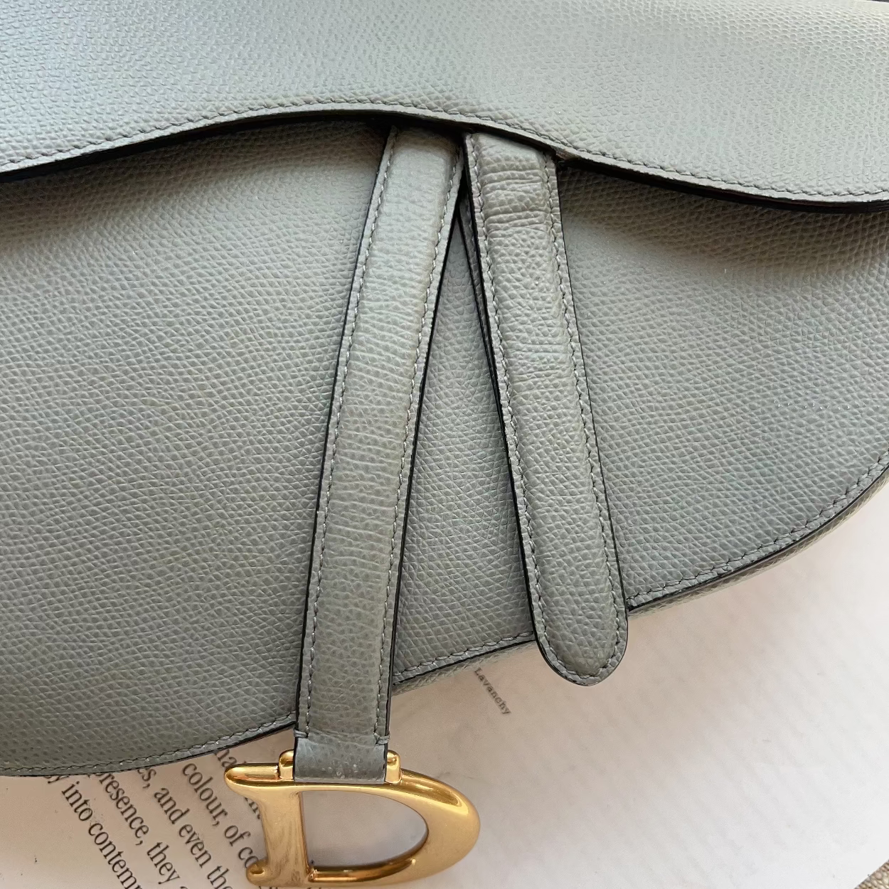 Gray leather handbag with a gold clasp on a textured surface