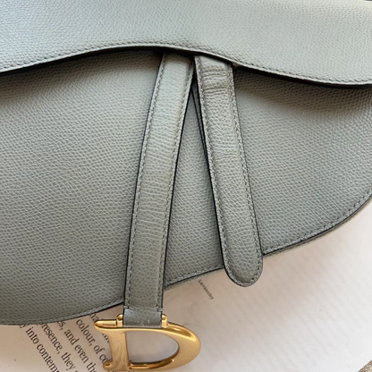 Gray leather handbag with a gold clasp on a textured surface
