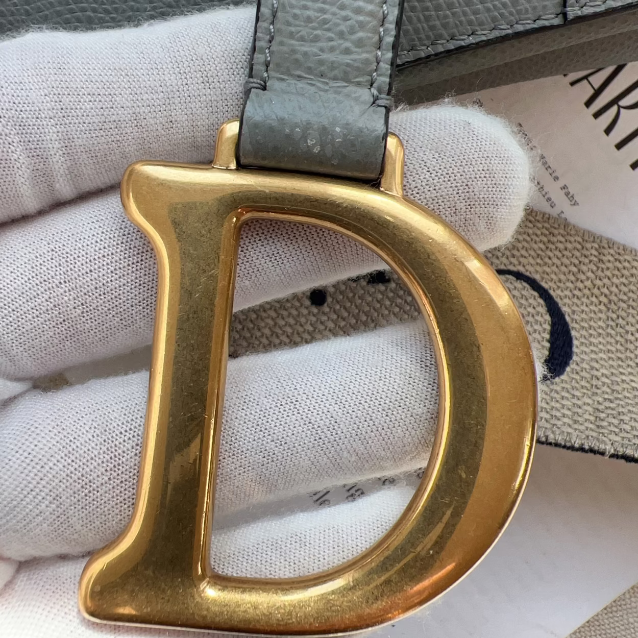 Gold belt buckle on a gray belt with a white cloth background
