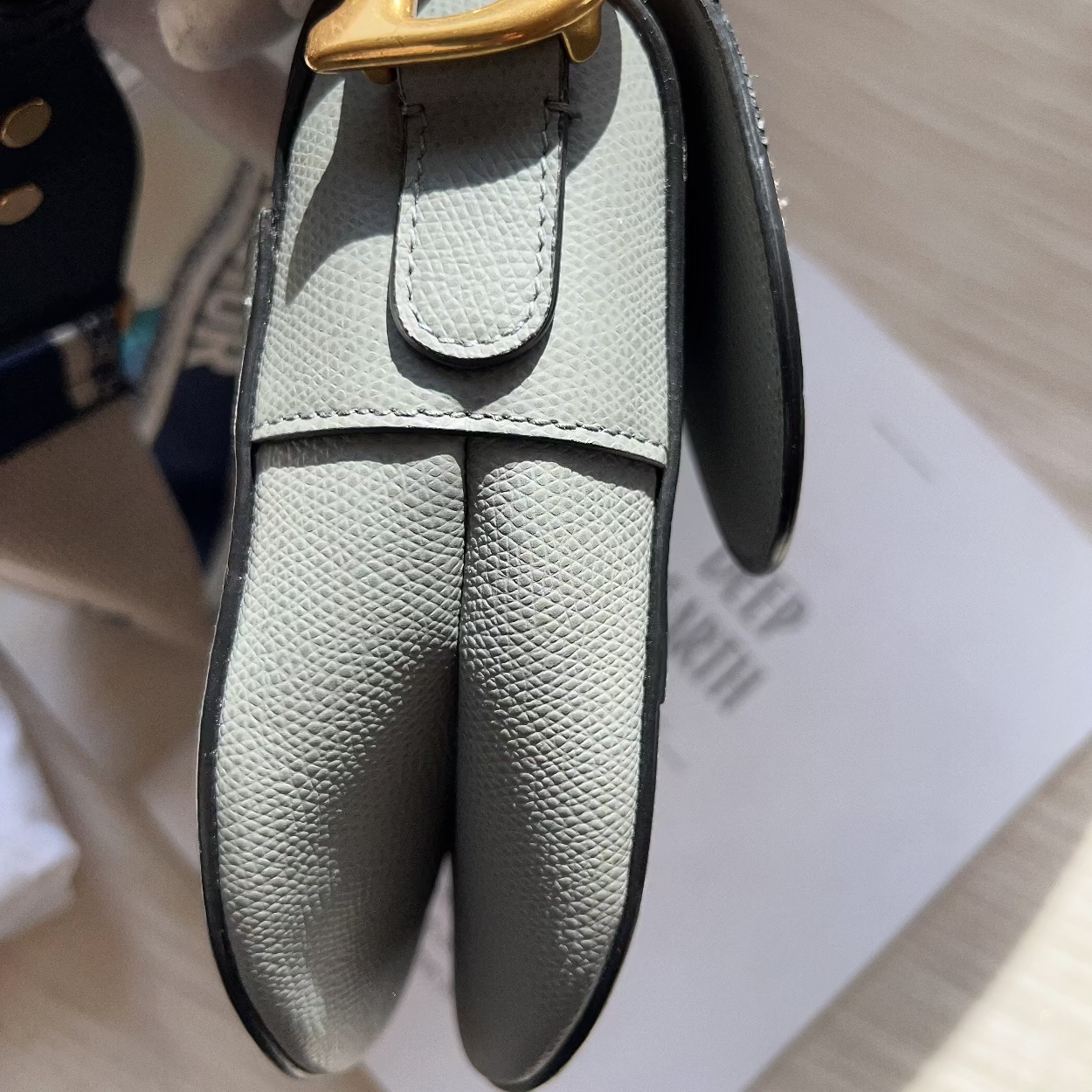 Gray leather keychain with gold clasp on a light background