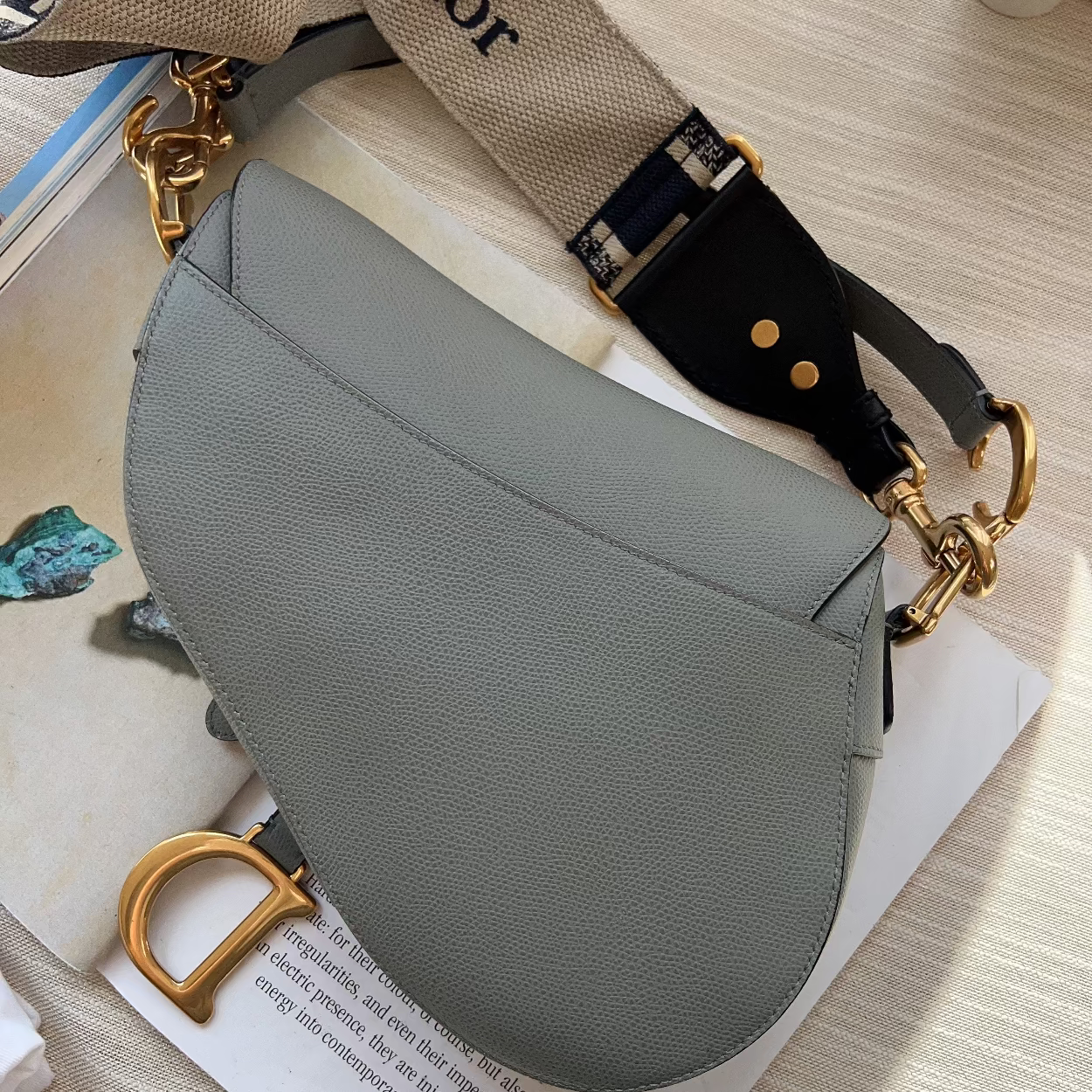 Gray handbag with gold hardware on a light wooden surface