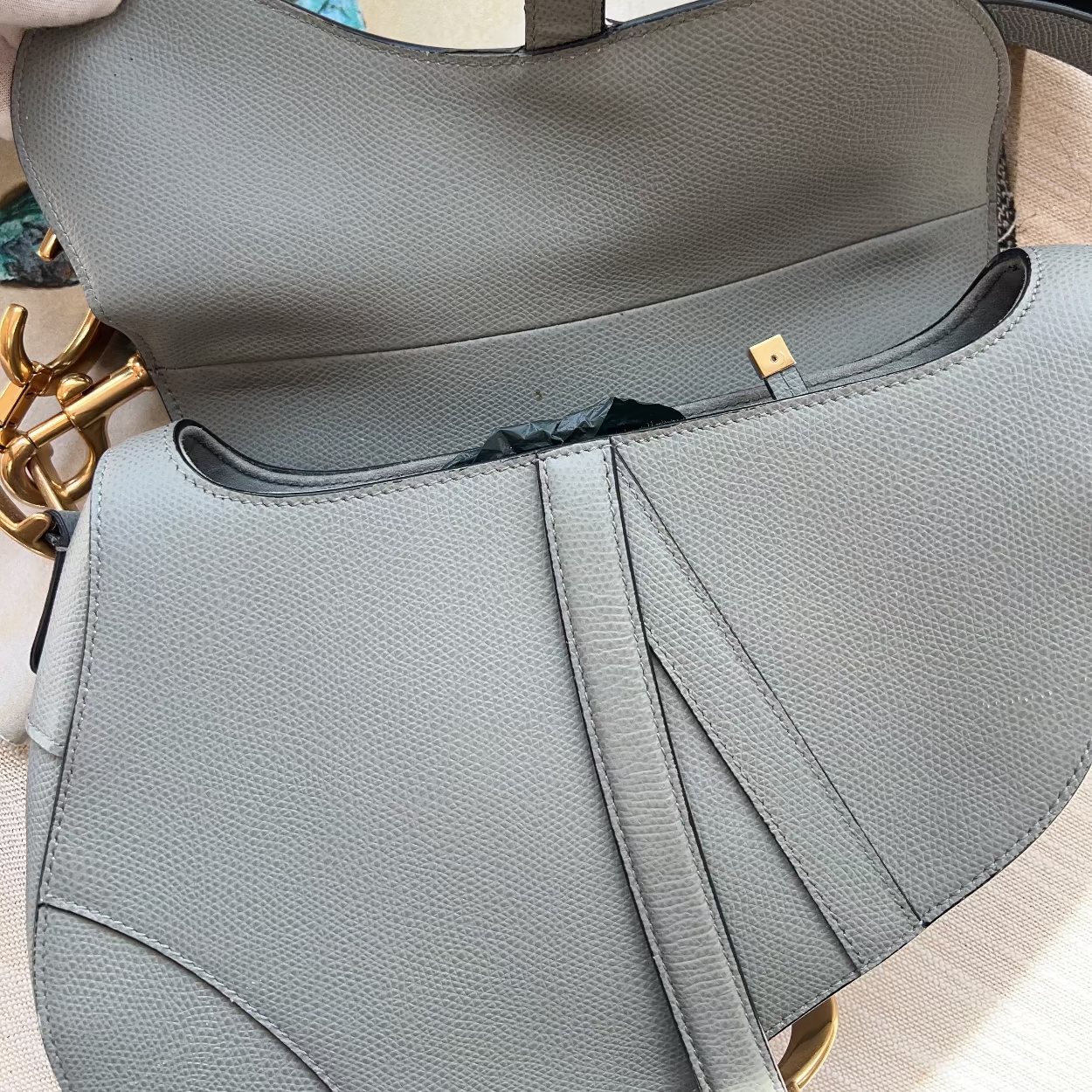 Gray handbag with gold accents on a light wooden surface