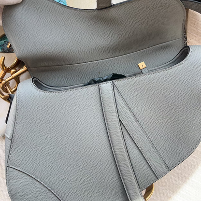 Gray handbag with gold accents on a light wooden surface