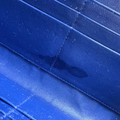 Close-up of a blue textured material with stitched paneling and a dark stain or wet spot visible near the center.