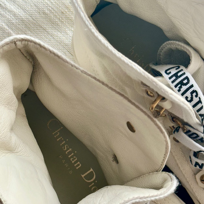 Close-up of the interior of a Christian Dior handbag in off-white leather, showing the brand name printed on the lining and a white ribbon with black lettering.