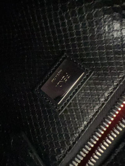Close-up of a black textured leather wallet or clutch with a metallic silver-tone 'F. R.