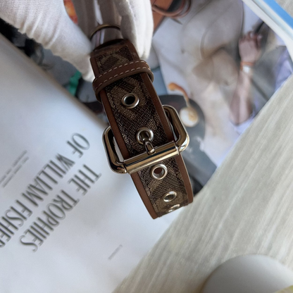 Brown leather dog collar with gold buckle on a book