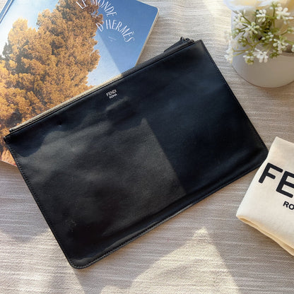 Black leather wallet and Fendi cleaning cloth on a textured surface with flowers.