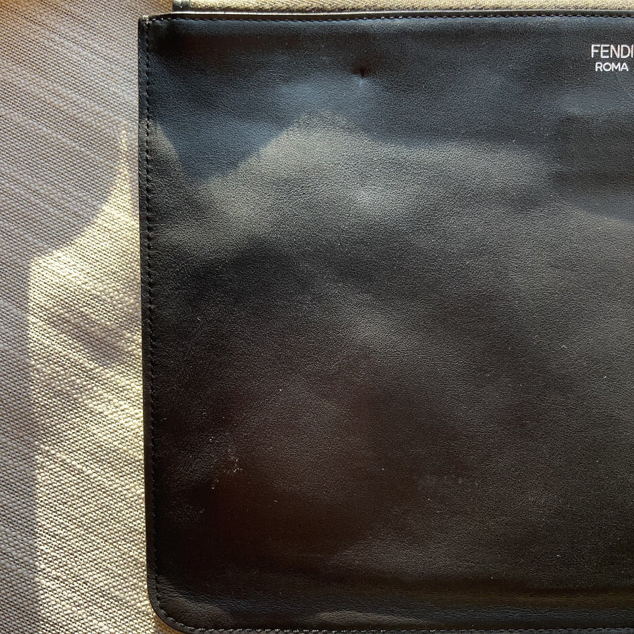 Black leather pouch with 'Fendi' branding on a textured surface