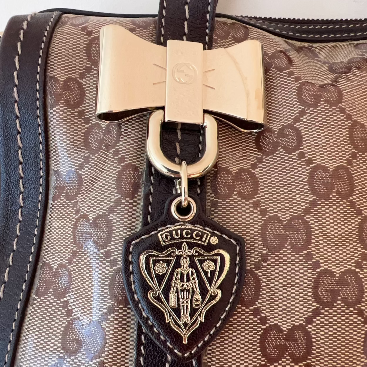 Gucci handbag with monogram pattern and bow detail on a white background