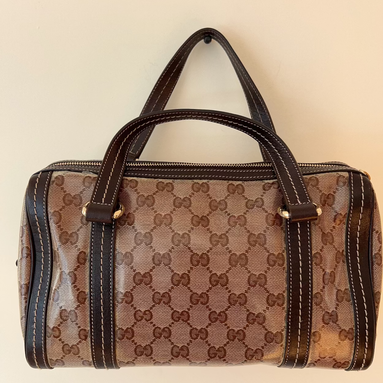Designer handbag with a prominent brand logo on a beige background