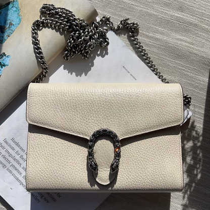 Beige handbag with a decorative clasp on a textured surface