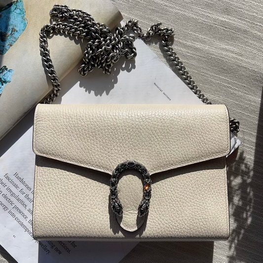 Beige handbag with a decorative clasp on a textured surface