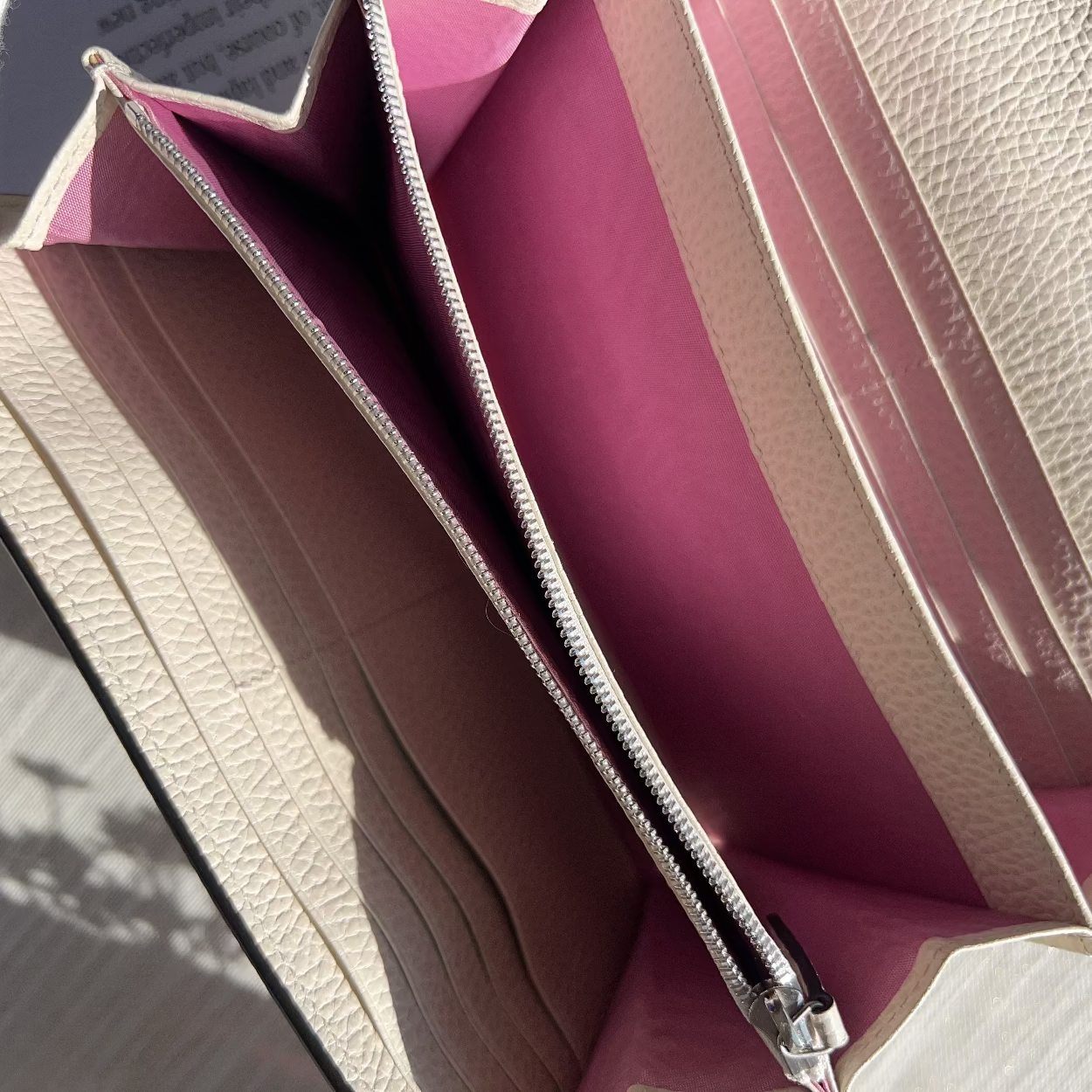 Close-up of a pink and beige leather wallet with a zipper.