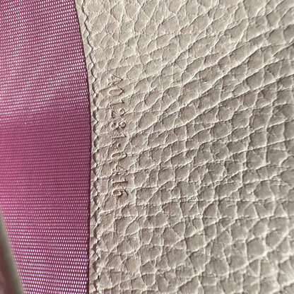 Close-up of textured pink fabric and beige leather surface with visible stitching.