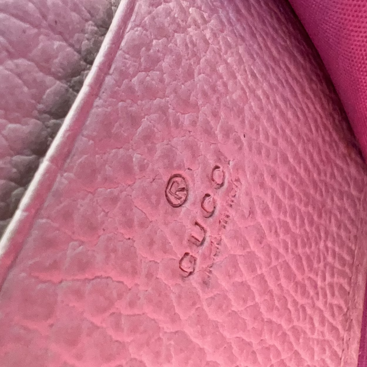 Close-up of a pink textured surface with a Gucci logo.