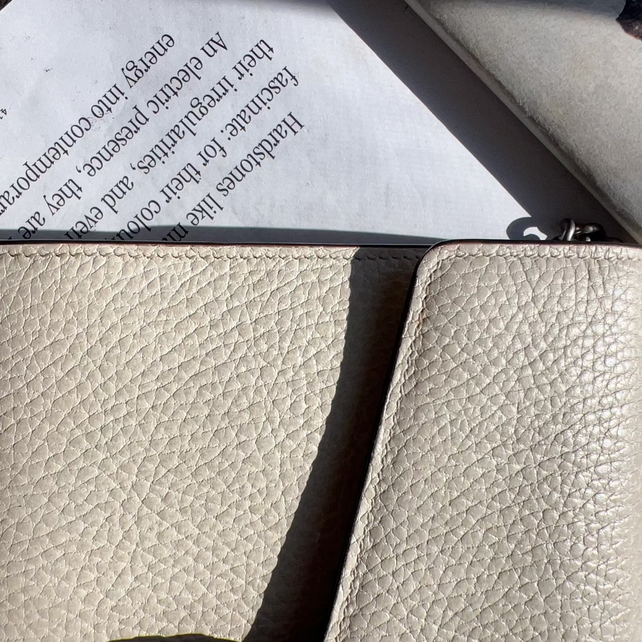 Beige leather wallet on top of a book with text