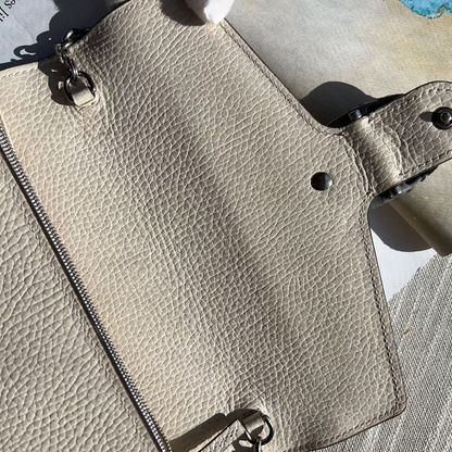 Close-up of a beige leather wallet with metal accents on a textured surface.