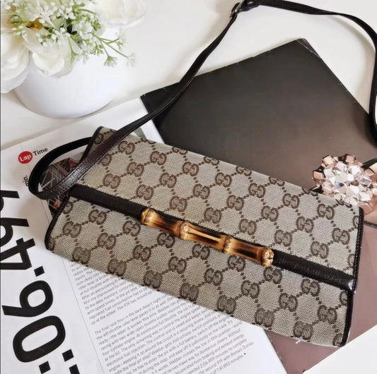 Designer handbag with gold hardware on a magazine with flowers and jewelry in the background