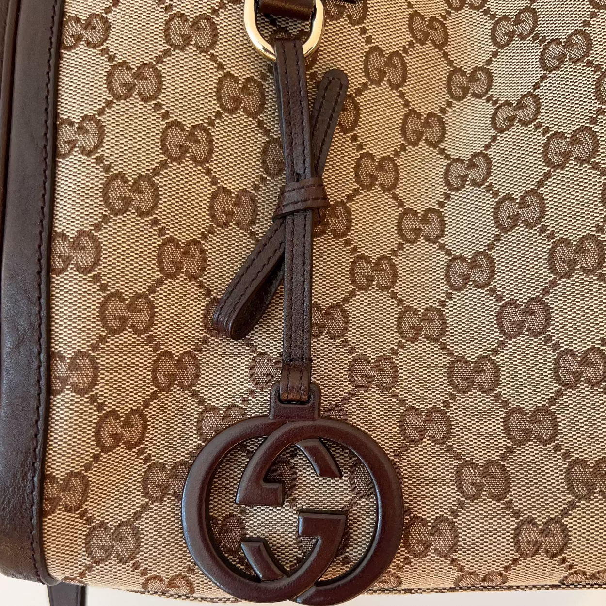 Close-up of a Gucci handbag with monogram pattern and interlocking G logo.