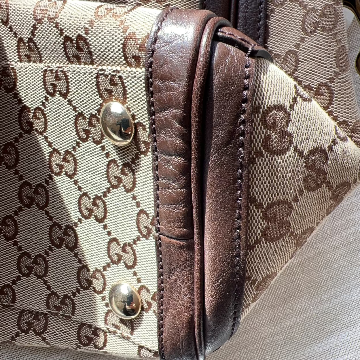 Close-up of a Gucci handbag with brown leather accents and monogram pattern.