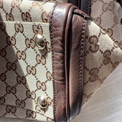 Close-up of a Gucci handbag with brown leather accents and monogram pattern.