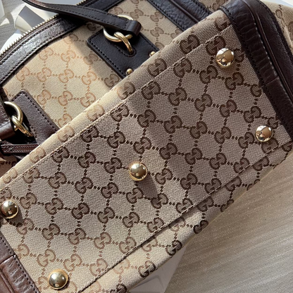 Close-up of a patterned handbag with gold accents on a light wooden surface.