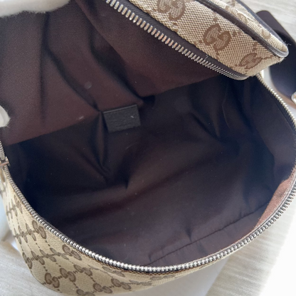 An open beige and brown monogram handbag or pouch with a dark brown interior, shown close up on a light surface.