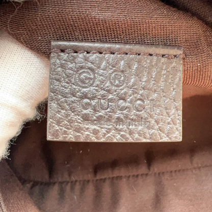 Close-up of a Gucci leather interior label stamped with the brand name and logo, set against brown fabric.