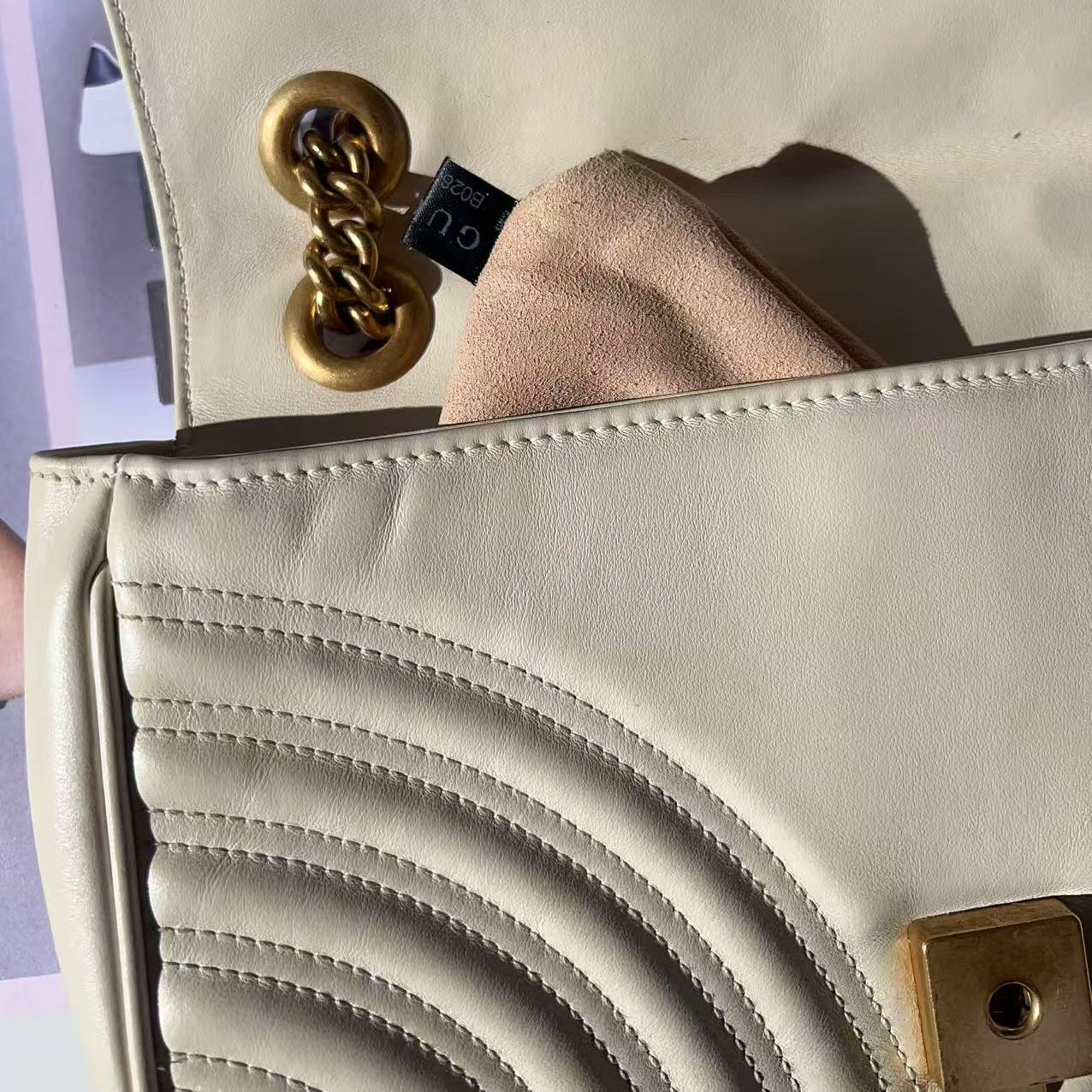 Close-up of a beige handbag with a gold chain detail.