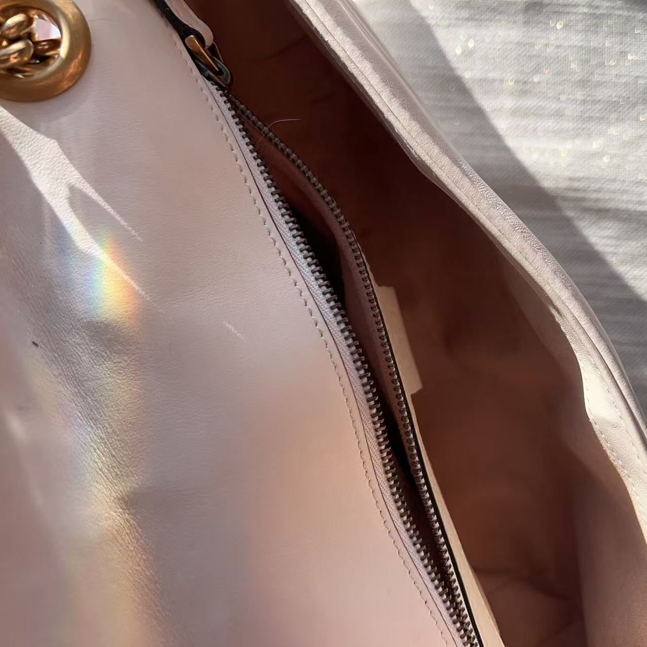 Close-up of a beige handbag with a gold zipper and handle.