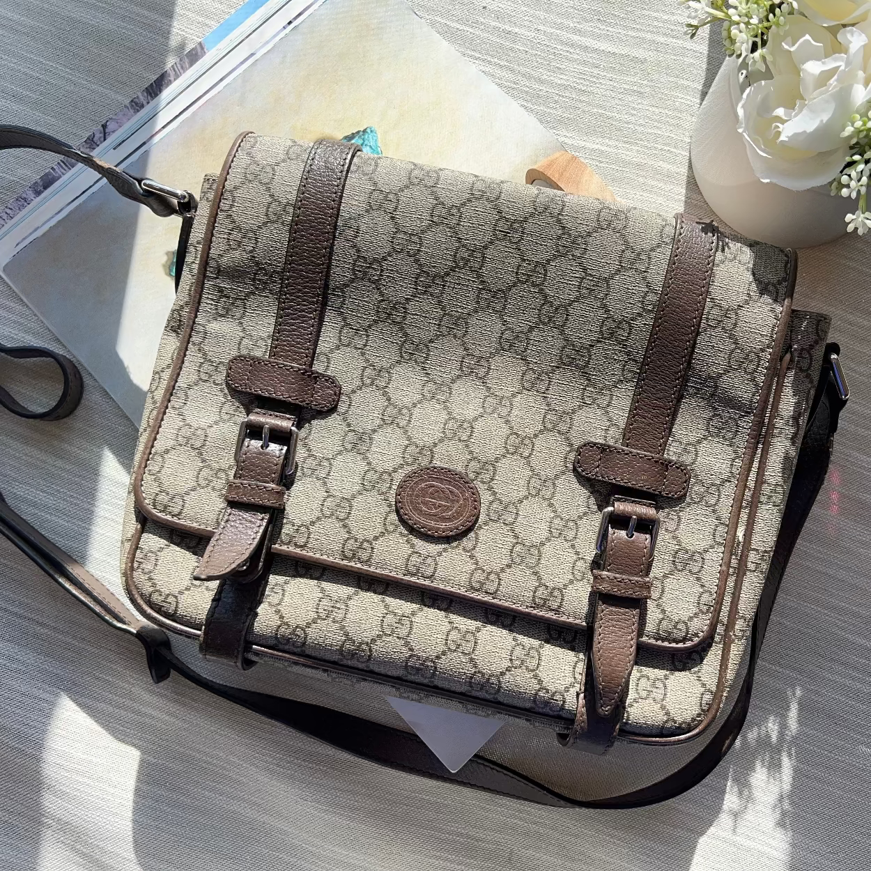 Designer handbag on a table with flowers and papers