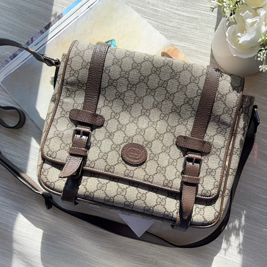 Designer handbag on a table with flowers and papers