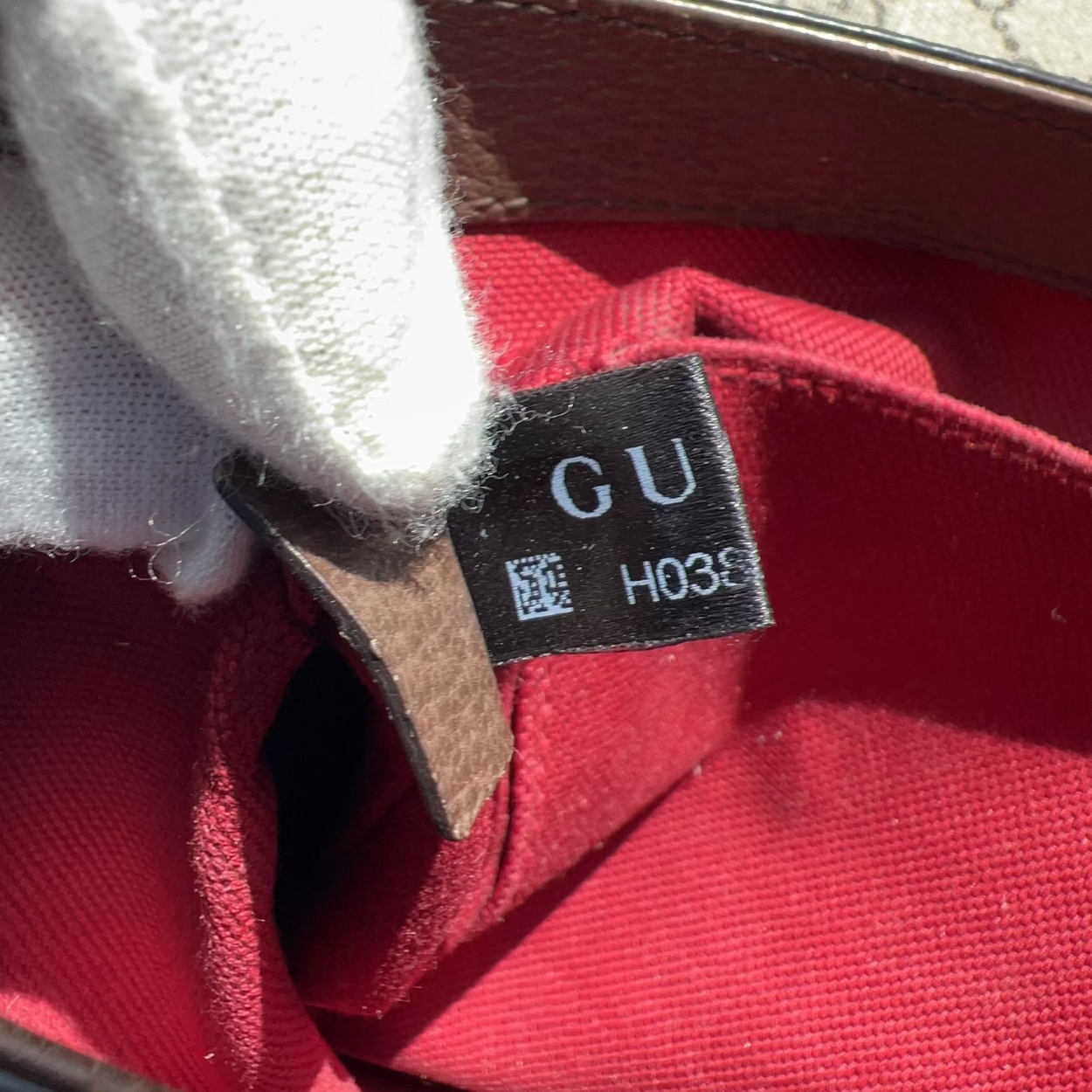 Close-up of a red fabric with a Gucci tag on a blurred background