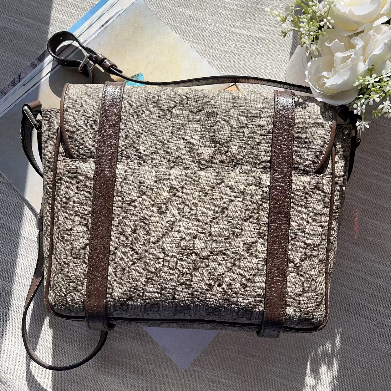 Patterned bag with brown strap on a textured surface with flowers