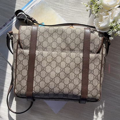 Patterned bag with brown strap on a textured surface with flowers